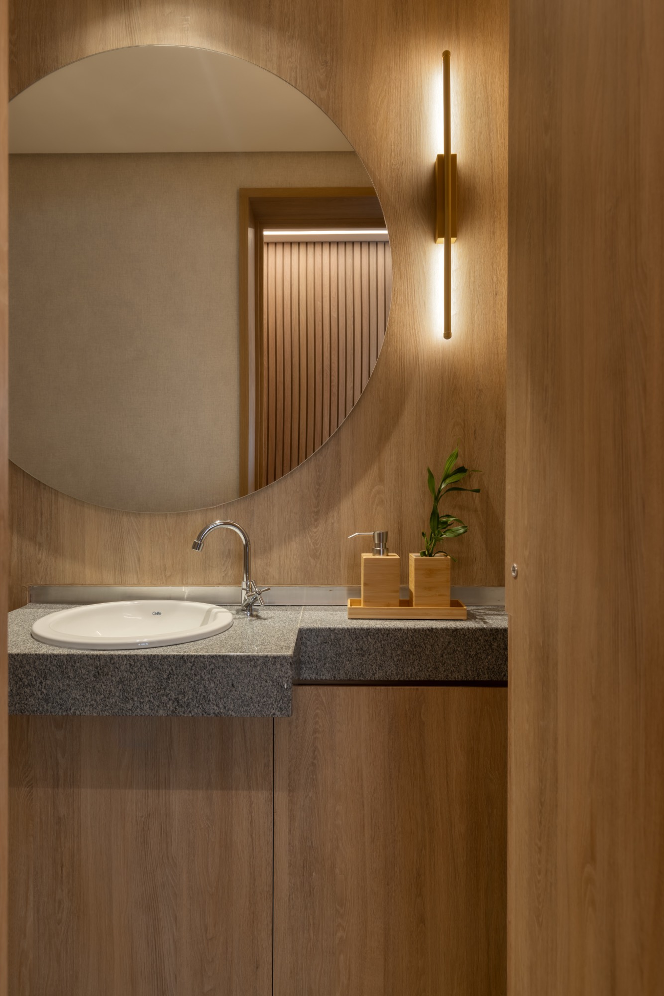 Lavabo com marcenaria de madeira, espelho redondo e arandela