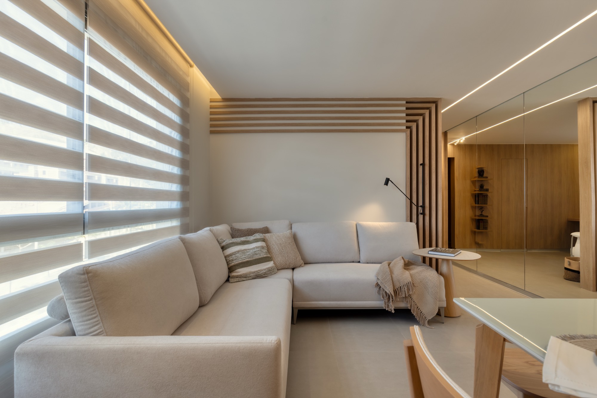 Sala de estar com sofá de canto e painel ripado
